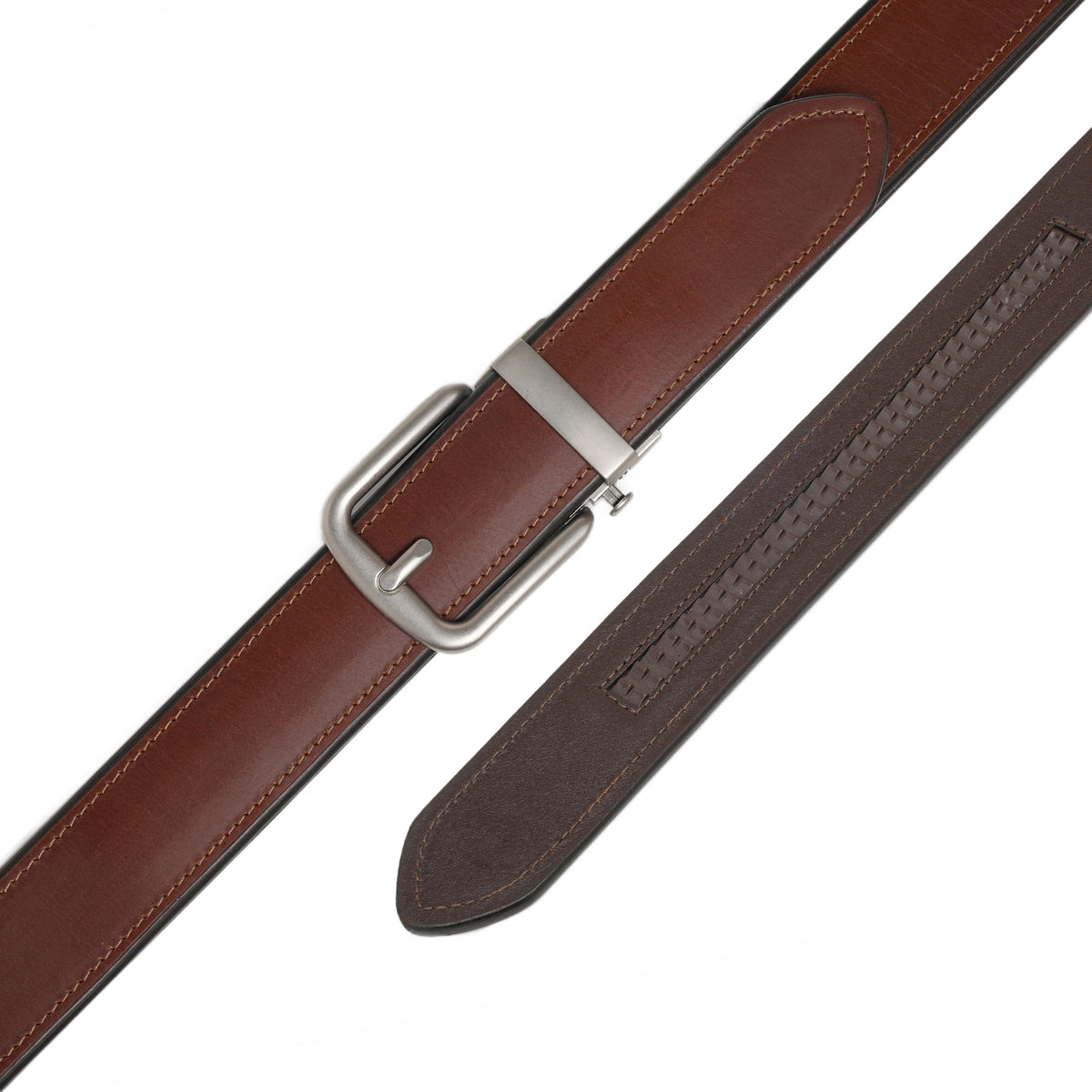 Cognac leather ratchet belt laid flat with its detachable buckle and visible adjustment track